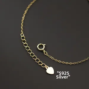 Detail of S925 sterling silver cross bracelet with gold finish and heart charm