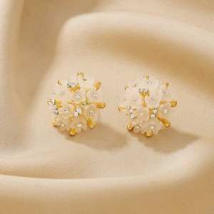 Close-up of 18K gold flower cluster earrings with white petals and zircon pearls on silk