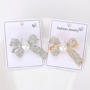 Close-up of golden and silver bow brooches with inlaid pearls and sparkling rhinestones