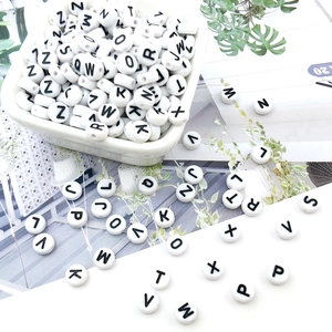 Macro view of round white resin alphabet beads with black uppercase letters for DIY crafts
