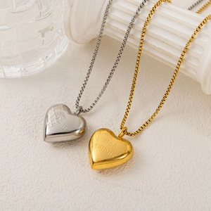 Detail of silver and gold heart necklaces with mon amour engraving on a box chain