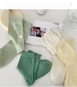 Detail of four-color cotton mid-calf socks with floral eyelet pattern and wavy edges
