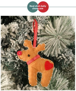 Détail d'un renne en feutre fait main avec cœur rouge accroché à un sapin de Noël enneigé