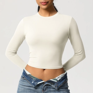 Détail du t-shirt de yoga moulant crème à manches longues et tissu élastique respirant