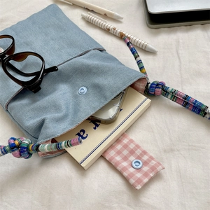 Detailed view of the embroidered denim tote bag interior with a pink checkered cotton lining