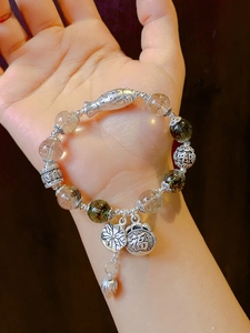 Close-up of silver and green ghost crystal beaded bracelet with lotus and fortune bag charms