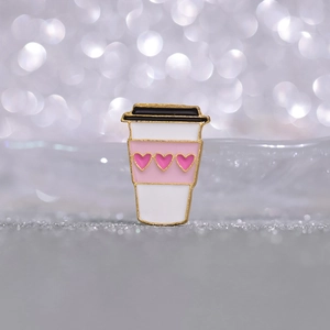 Macro d'un pin's en émail en forme de tasse à café rose avec motifs de petits cœurs