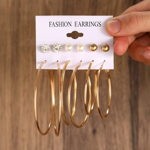 Detail of a multi-pair gold earring set with hoops, pearls, and rhinestones on card