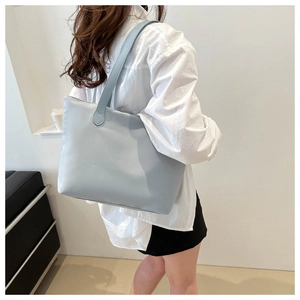 Detail view of a light blue large capacity tote bag carried by a model over the shoulder