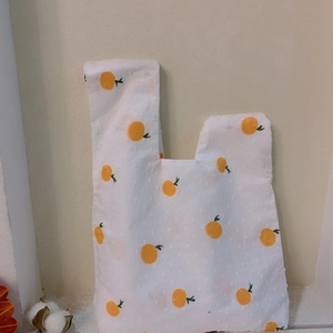 Detail of white knot wrist bag with orange print and 3D textured polka dot fabric