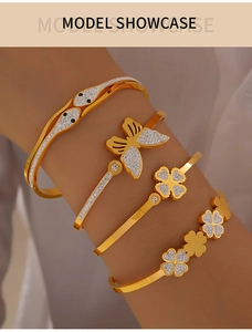 Close-up of gold-plated titanium steel bracelets with clover and butterfly charms on a model