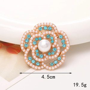 Détail d'une broche fleur de 4,5 cm avec strass bleus et une grande perle centrale