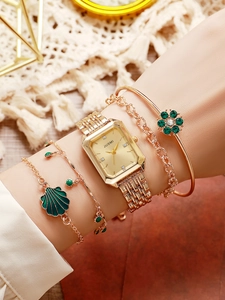 Detail of gold square watch and emerald flower bracelet set on a female wrist