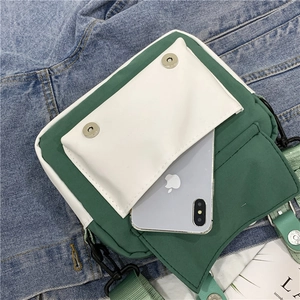 Detail of green canvas crossbody bag with white front pocket on denim jacket background