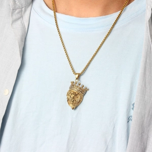 Detail of a gold lion head pendant with a diamond crown worn by a male model