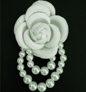 Detail view of white camellia brooch with layered petals and elegant pearl tassels