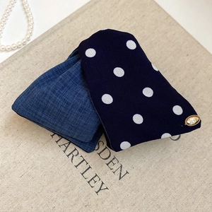Close-up of polka dot fabric hair scrunchie with a gold Love tag and denim texture