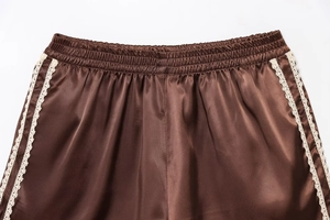 Detailed macro view of brown satin shorts featuring elastic waist and white lace trim
