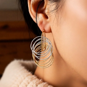 Close-up of stylish layered gold and silver hoop drop earrings worn by a model
