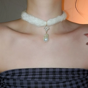 Detailed macro view of an elegant plush choker with baroque pearl and rhinestone clover charm
