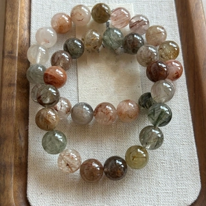 Macro view of multi-color rutilated quartz beaded bracelets on wooden tray decoration