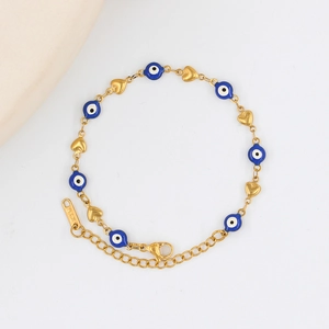 Macro detail of gold-plated heart charms and evil eye beads on a polished chain bracelet