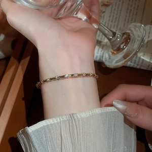 Close-up of a gold bamboo-style zircon bangle worn by a model in elegant indoor lighting