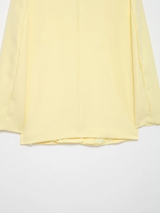 Detail view of the yellow blazer back hem showing smooth fabric texture and stitching