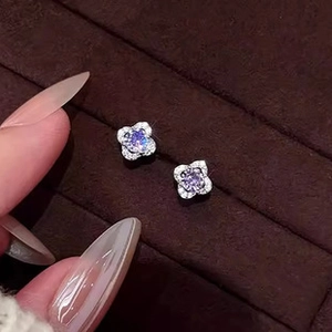 Detail view of flower-shaped earrings with purple center stone and white diamonds
