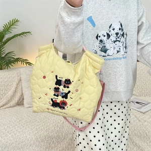 Detail of light yellow quilted tote bag with cute black cat embroidery and pink strap