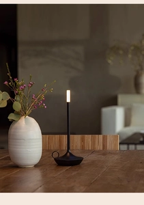Close-up of a matte black LED portable table lamp on a wooden desk with warm lighting