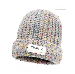 Detailed close-up of gray speckled knit beanie with soft colorful yarn accents and a woven label