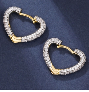 Macro shot of two-tone heart earrings with pave-set cubic zirconia on blue background