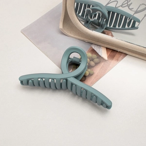 Detail of large matte grey-blue shark hair claw clip on desk with vintage mirror