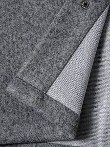 Macro detail of grey felt fabric with white mesh lining and a dark metal snap button