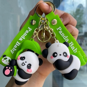 Close-up of cute panda keychains with green silicone straps and golden metal accessories
