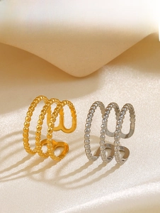 Detail of beaded three-layer open ring in gold and silver finish on silk background