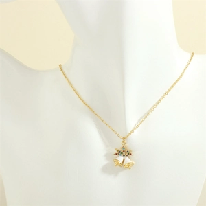 Close-up of gold chain necklace with white enamel bells and colorful zircon pendant