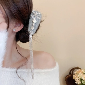 Detail of grey flocked hair clip with sparkling rhinestones and long tassel on a model
