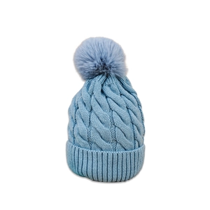 Detail view of light blue cable knit beanie with fluffy faux fur pompom for winter warmth