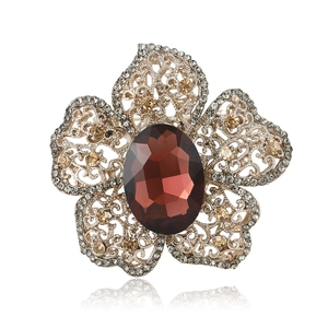 Broche fleur vintage dorée avec pierre précieuse rouge et cristaux sur fond blanc