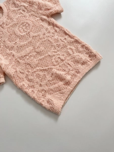 Gros plan sur le haut en maille bouclée rose avec jacquard floral et texture grainée douce