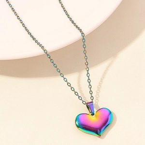 Detailed view of rainbow gradient heart pendant on a thin cross chain accessory