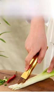 Macro view of golden stainless steel scallion shredder slicing green onions on wood
