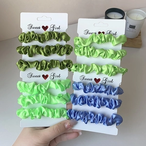 Three-piece set of glossy satin scrunchies in green and blue on display card
