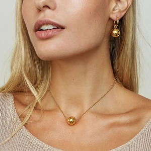 Minimalist gold ball pendant necklace and matching earrings set on model