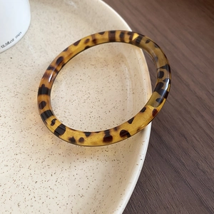 Detailed view of irregular tortoiseshell acrylic bangle on a ceramic tray