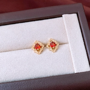 Vue détaillée des boucles d'oreilles vintage en forme de fleur avec pierres rouges en boîte