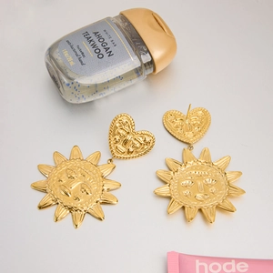 Détail de boucles d'oreilles cœur et soleil en or 18k avec motifs en relief vintage
