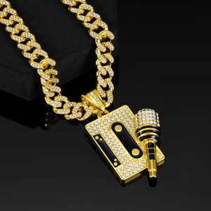 Close-up of gold iced-out cassette and microphone pendant on Cuban link chain necklace